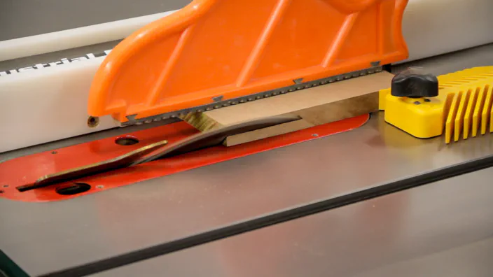 A bevel is cut in a piece of MDF on a table saw.