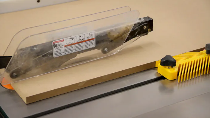 A piece of MDF is ripped on a table saw.