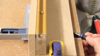 A pencil is used to mark a location on the MDF fence.