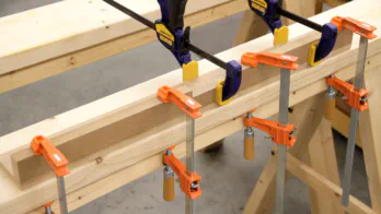 Glue and clamps are used to join two pieces of MDF.