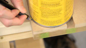 A can is used to trace a curve on the table top.