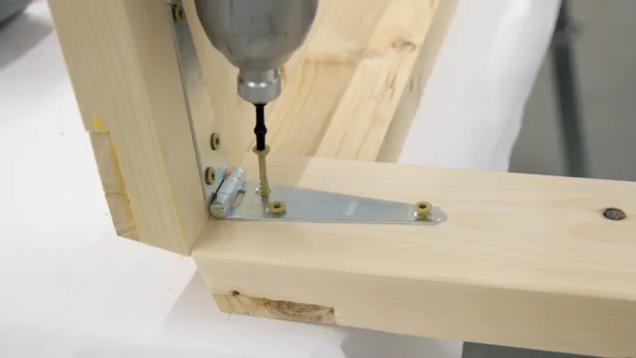 Screws are inserted into the second half of a strap hinge.