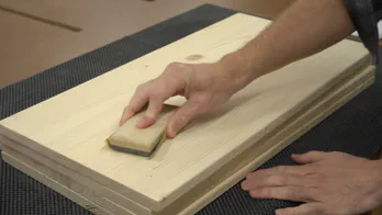 Wooden shelving is sanded.
