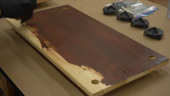 Gel stain is applied to wooden shelving.