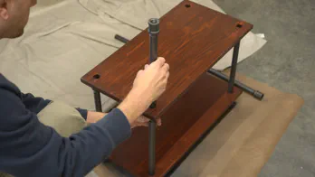Pipe legs are assembled with wooden shelving.