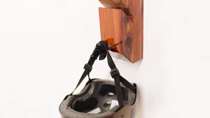 A helmet hanging from a cedar skateboard rack.