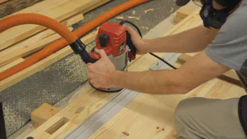 A router cuts a groove in the workbench top.