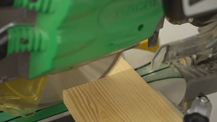 A miter saw cuts a board.