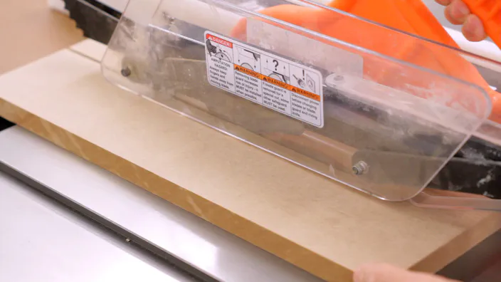 A piece of MDF is cut on a table saw.