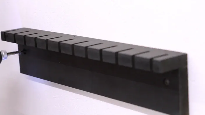 A drill is used to insert a screw into the rack.